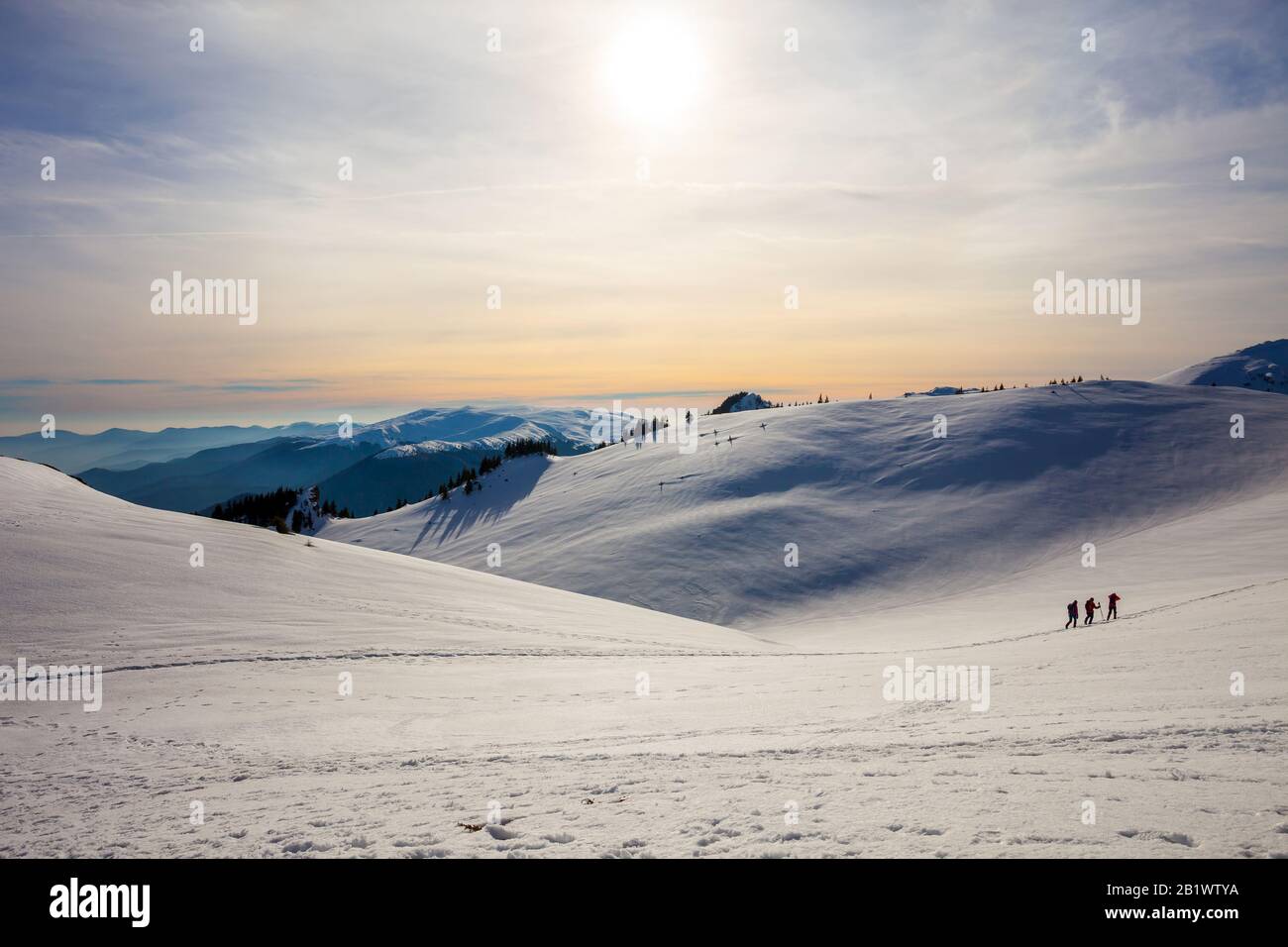 Hikers silhouette at dawn on Mount Ciucas in winter watching the sunset, part of Romanian Carpathian Range Stock Photo