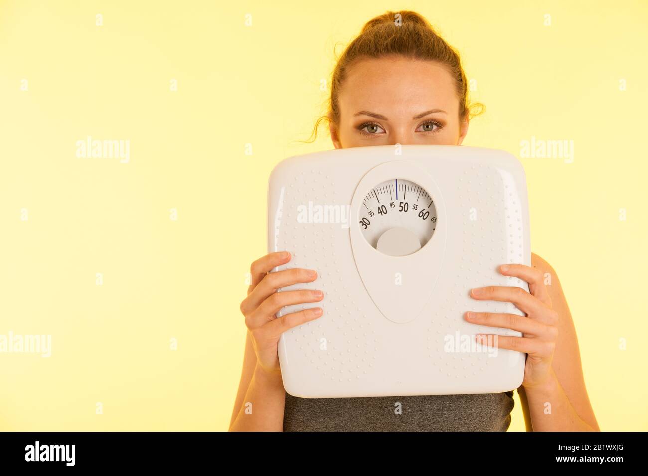 Beautiful young active fit woman hold scale as gesture of loosing