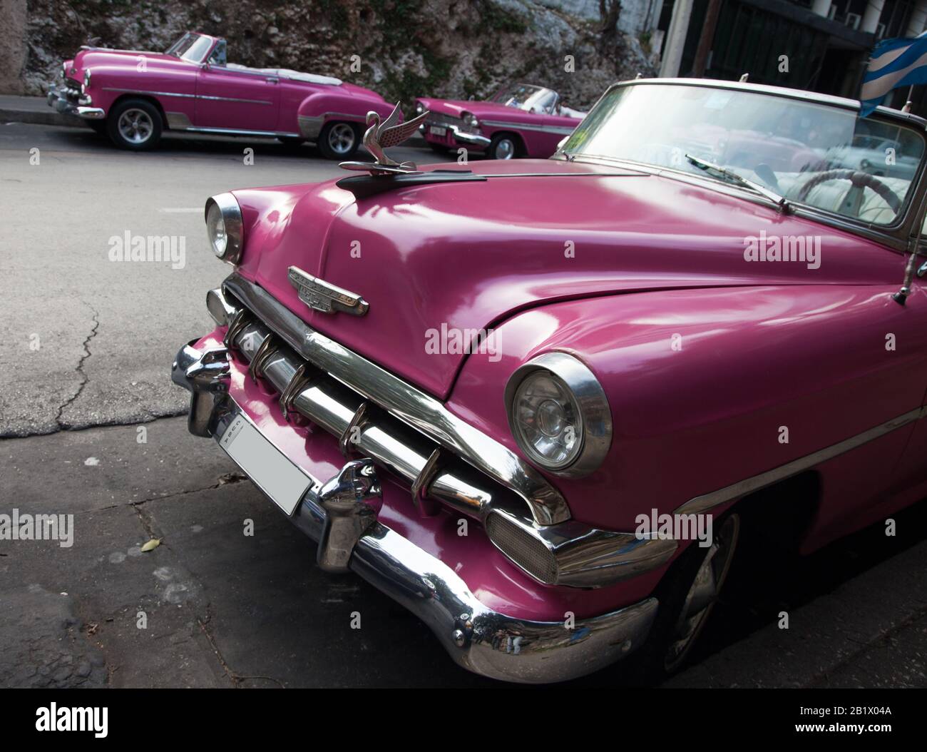 A group of three pink Chevrolet antique classic cars on a street in Cuba. Stock Photo
