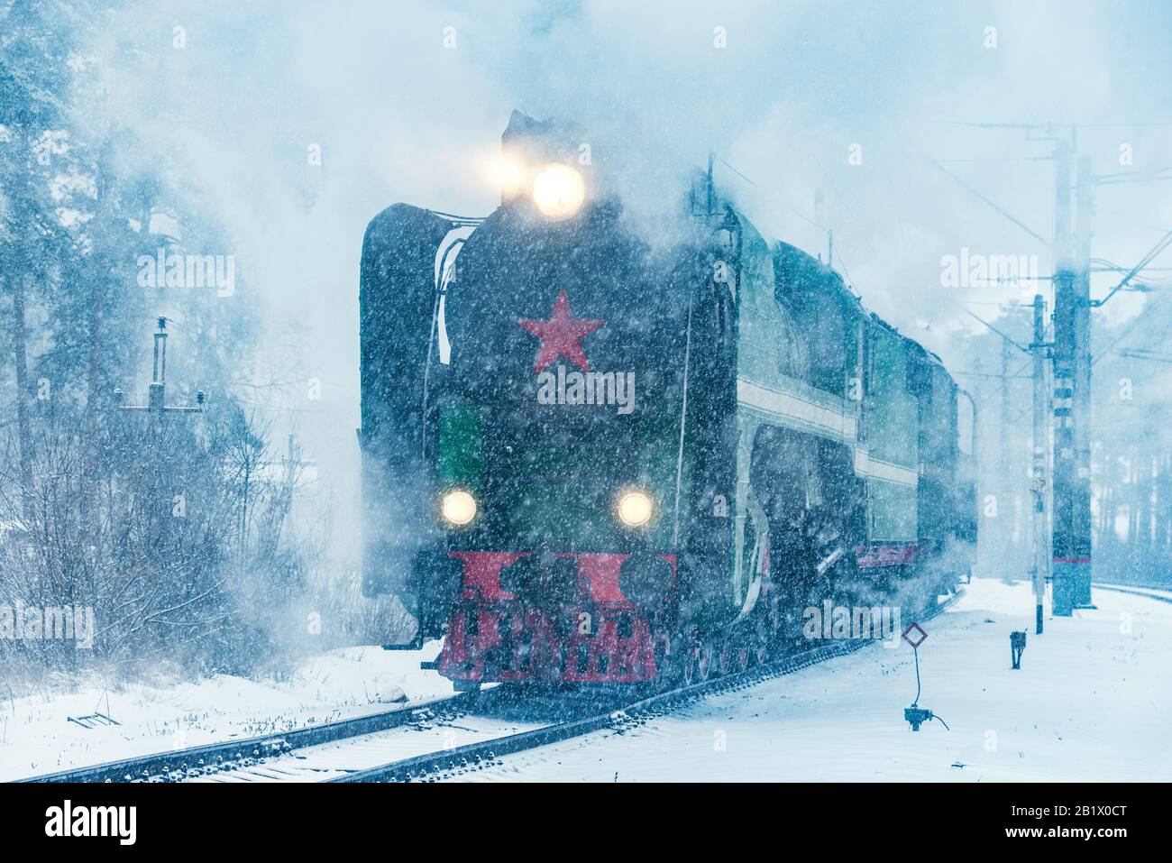 Retro steam train departs from the railway station at winter snowy time ...