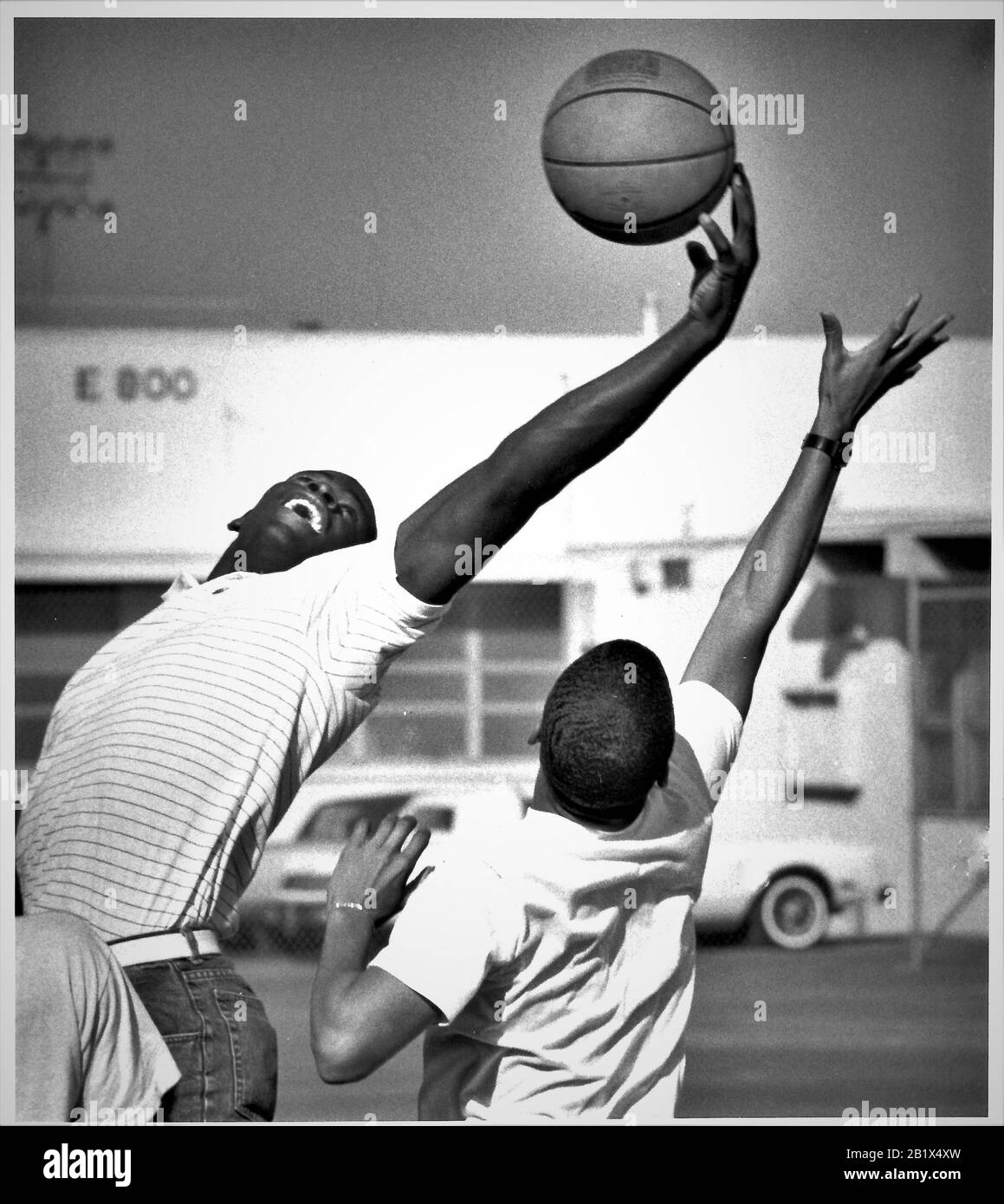 Basketball pickup game in school year with blocking shot and rebounding outside industrial work building at lunch time Stock Photo