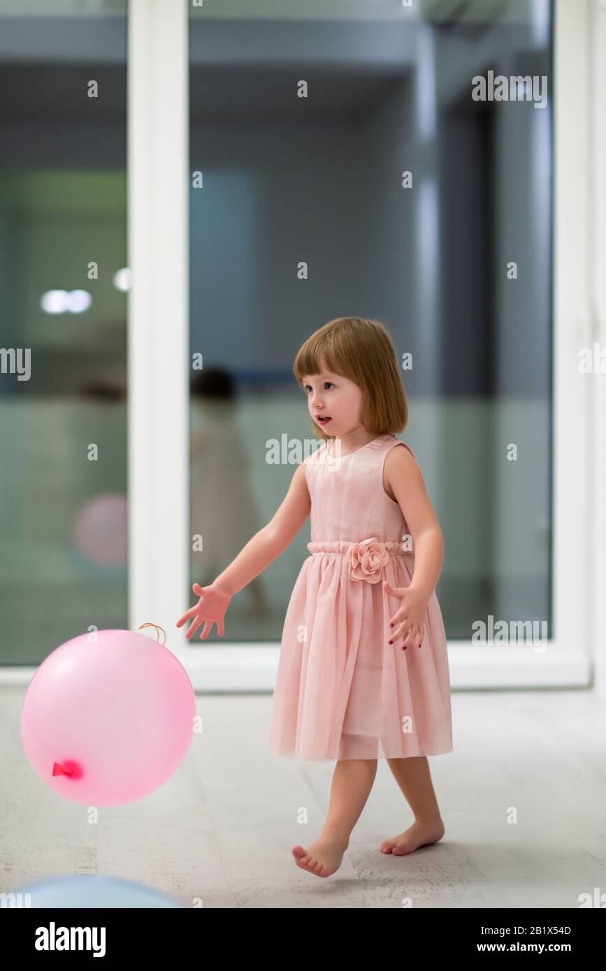 happy cute little girl in a pink dress enjoying while playing with ...