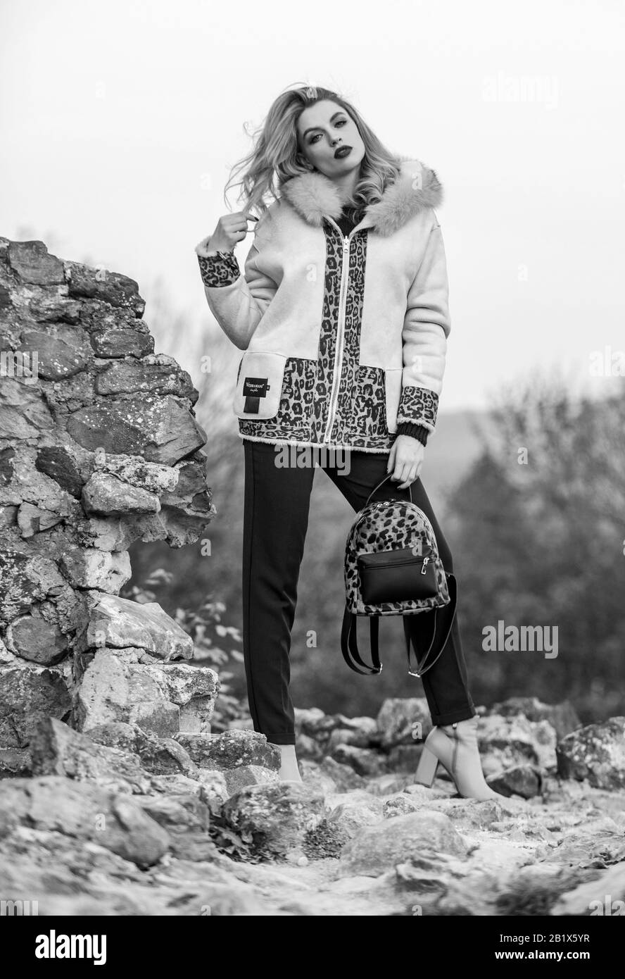 Beautiful day. warm short faux fur coat in fall. sexy woman red lipstick  nature background. autumn season clothes and accessory. girl long hair hold  backpack. woman leopard pattern half-length coat Stock Photo -