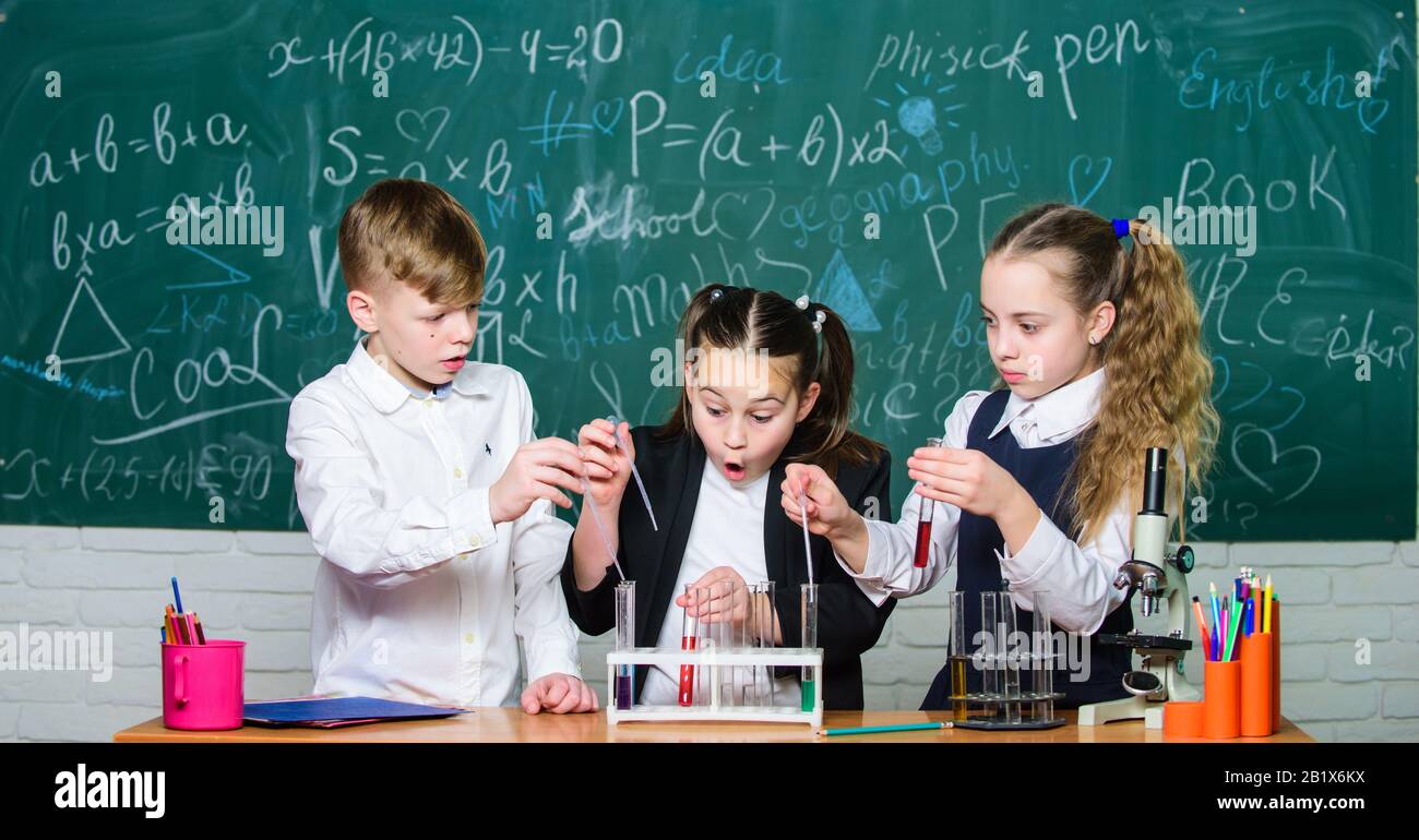 Girls and boy providing experiment with liquids. Test tubes with