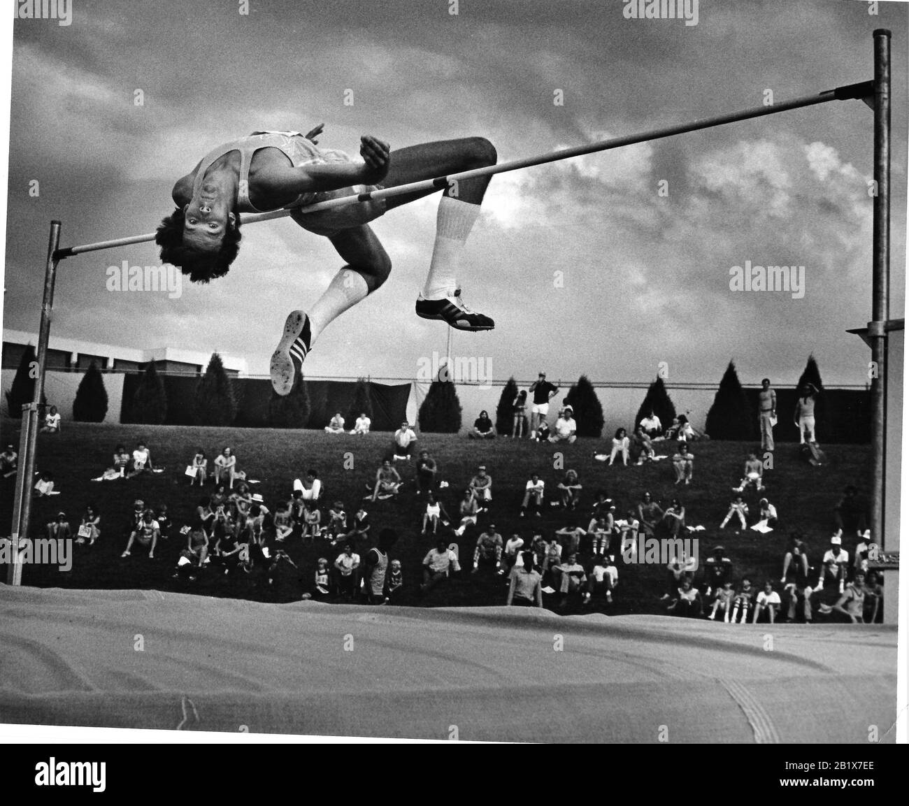 High jumper in Wichita during meet with clouds as he clears the height Stock Photo