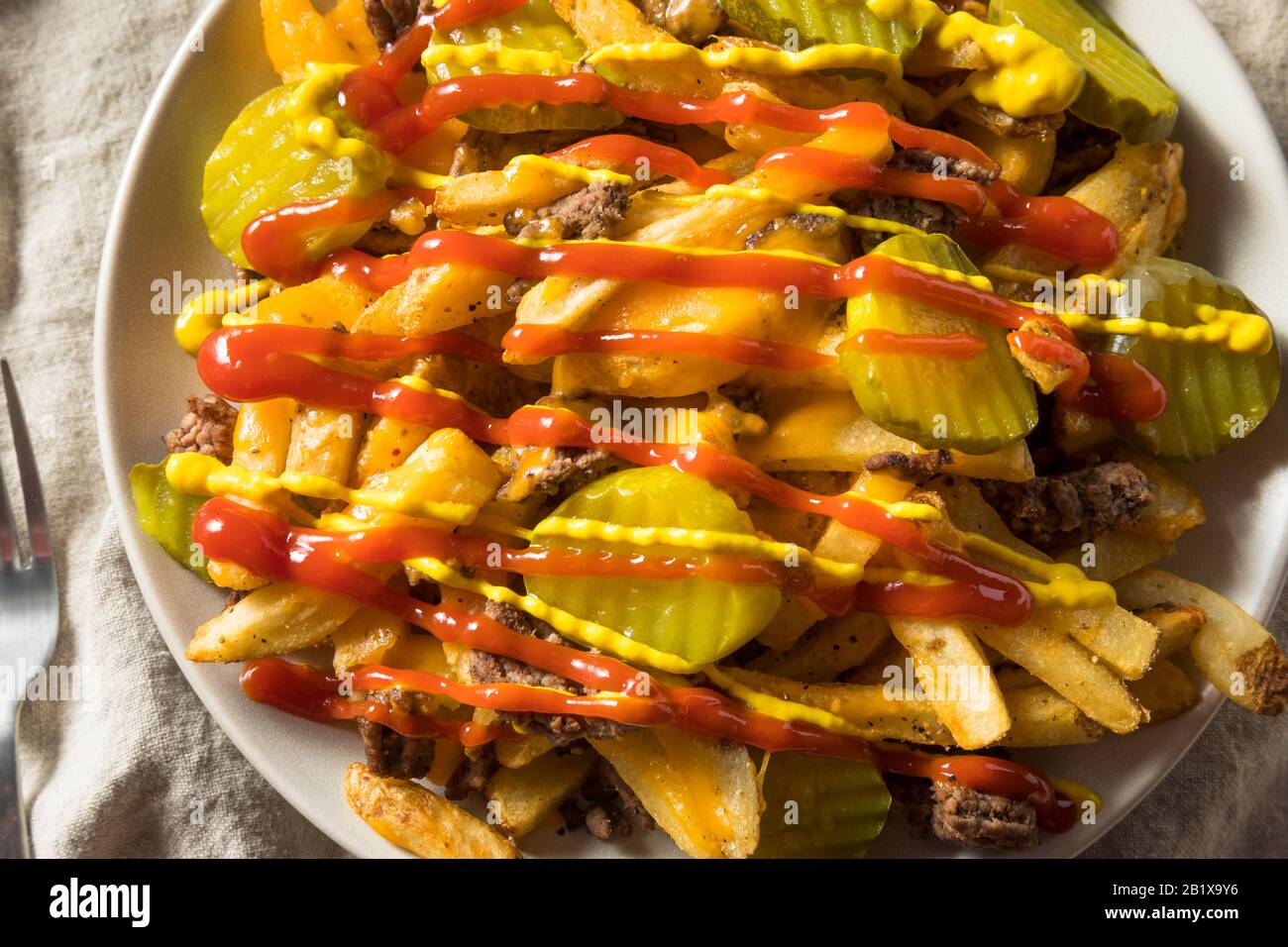 Homemade Loaded Cheeseburger Cheese Fries with PIckles and Ketchup Stock Photo