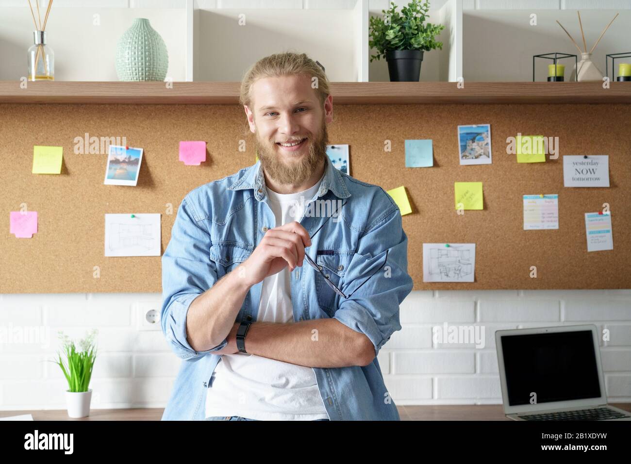 Smiling confident millennial man look at camera stand at workspace Stock Photo