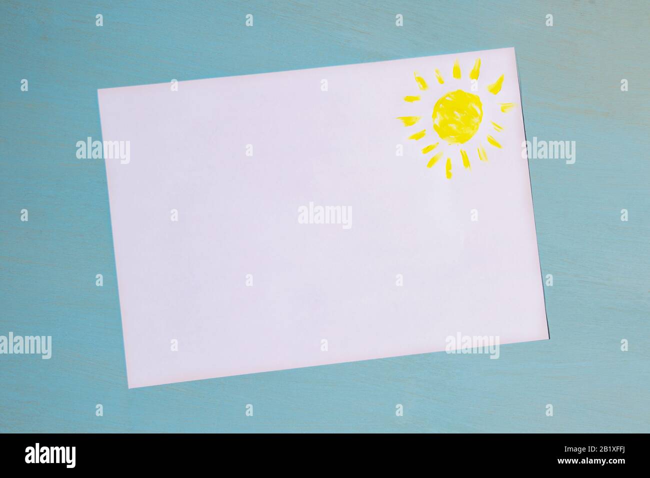 copyspace on White sheet of paper with blue background a place for the inscription and painted with a yellow sun Stock Photo