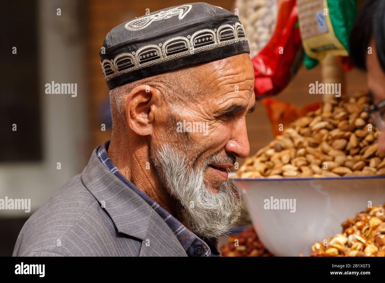 Profile of elderly, uyghur man with long, grey beard. He is wearing a traditional doppa (hat). Muslim uyghur minority in Xinjiang / China. Stock Photo