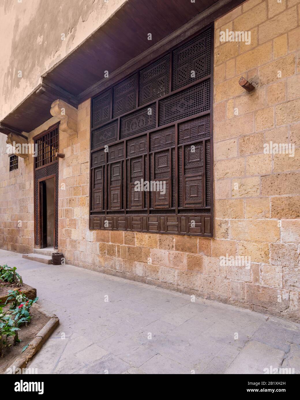 Wooden arabesque window, Mashrabiya, and door in exterior stone bricks wall of ottoman era old historic El Sehemy building, Moez Street, Cairo, Egypt Stock Photo