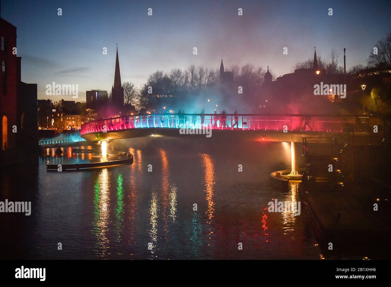 People cross Castle Bridge in Bristol, where an art installation titled Pink Enchantment, billowing smoke and flashing coloured lights is part of an immersive artwork as part of the first ever Bristol Light Festival. Stock Photo