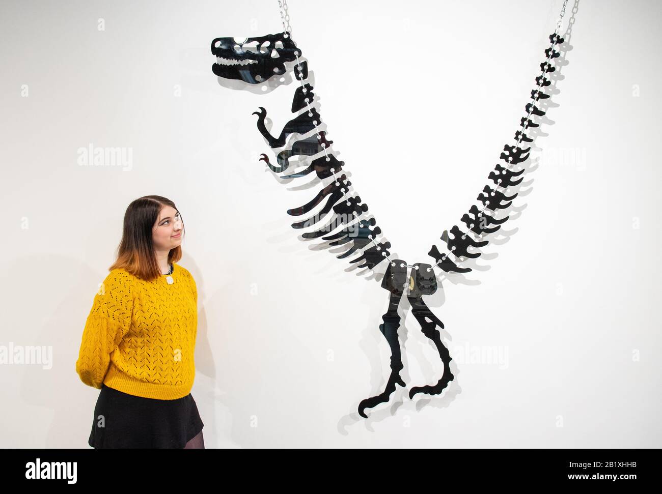 Ruth Davies-Mourby views a large scale reproduction of a Tatty Devine laser-cut acrylic dinosaur necklace, part of the 'Misshapes: the Making of Tatty Devine' exhibition, which features over 100 pieces from 20 years of the iconic British jewellery brand, at the Stephen Lawrence Gallery in London. Stock Photo