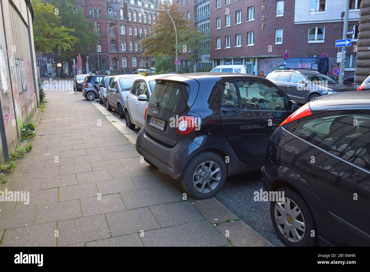 Smart Car Fortwo parked sideways with wheels on the pavement in an on street parking space in Hamburg, Germany. October 2019 Stock Photo