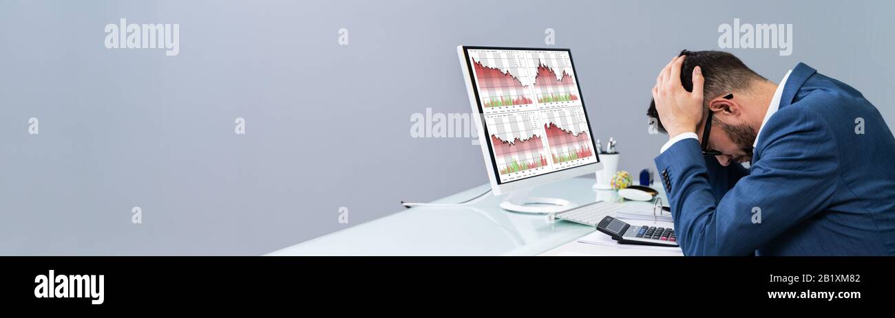 Despairing Businessman Faced With Financial Losses Looking On Graphs Dropping Into The Red Stock Photo