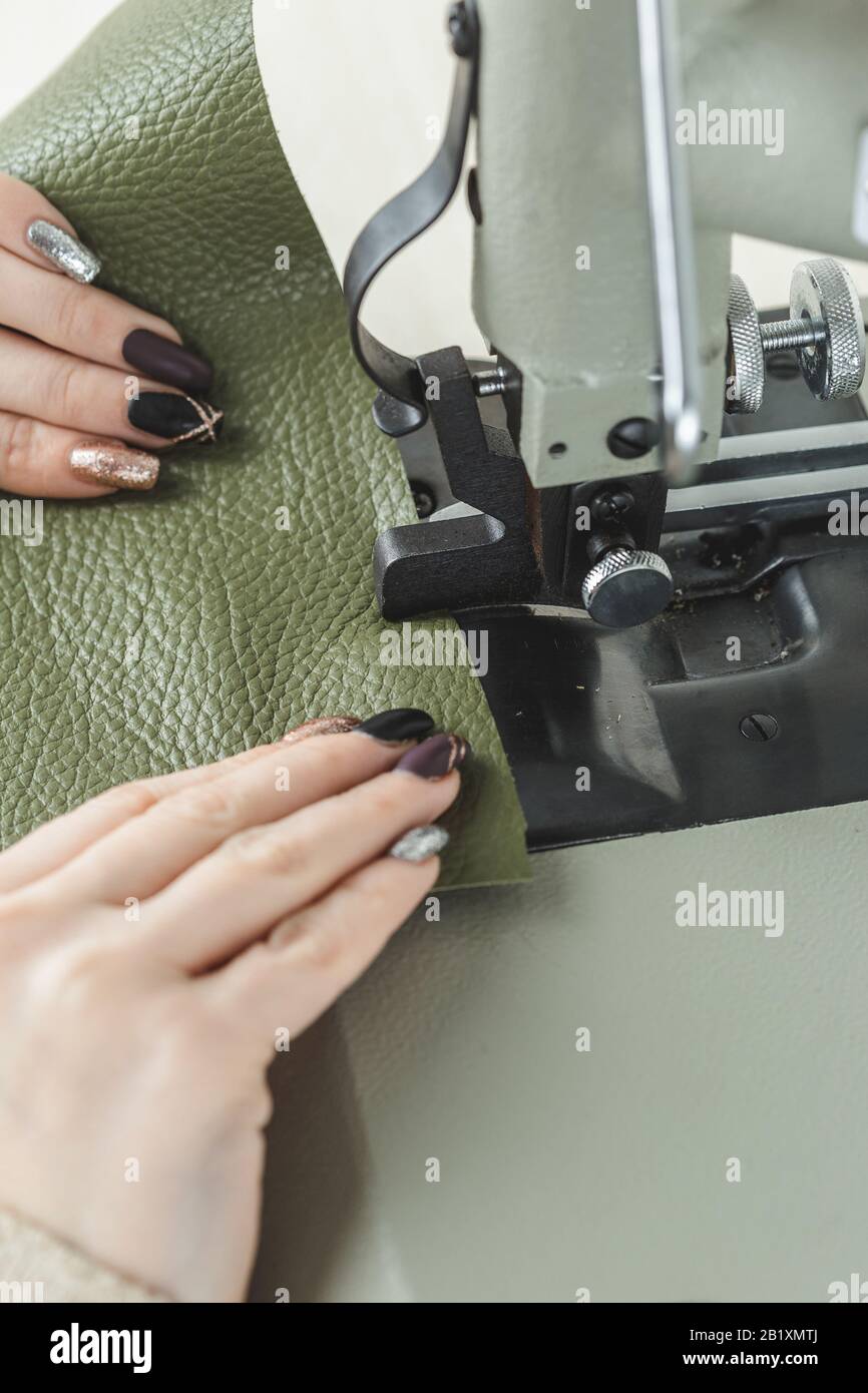 Young white woman stitching leather using a sewing machine Stock Photo