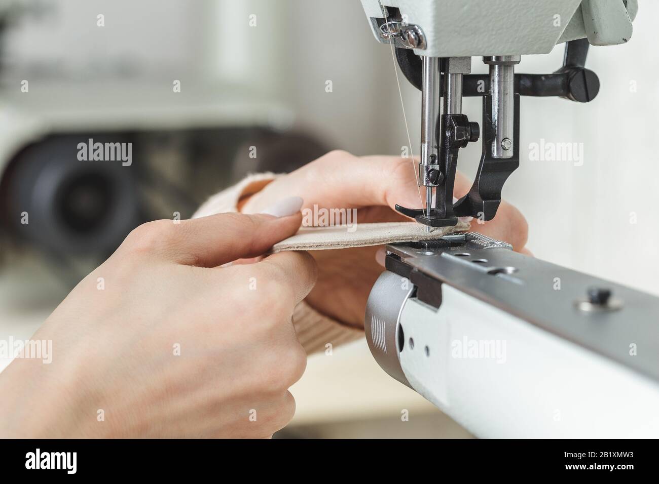 Young white woman stitching leather using a sewing machine Stock Photo