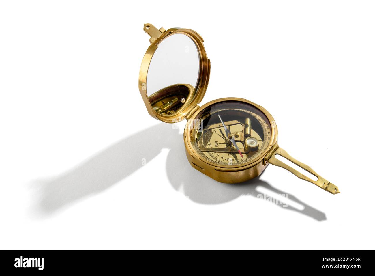 Old vintage brass compass opened up to show the magnetic needle inside over a white background Stock Photo