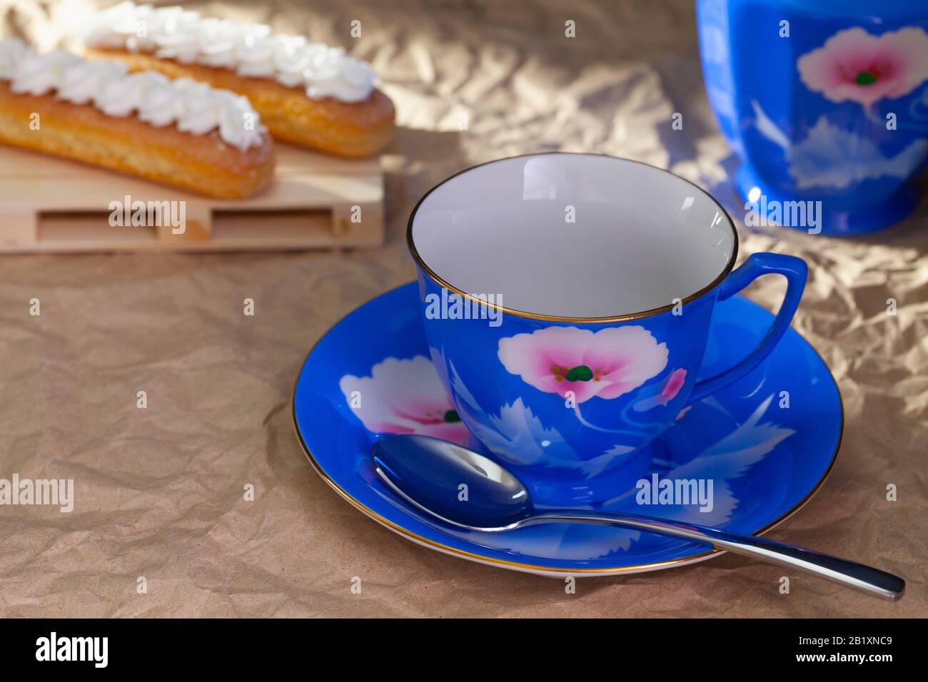 Blue Empty Cup of Tea, Teapot and Italian ladyfingers on table with crumpled paper Stock Photo