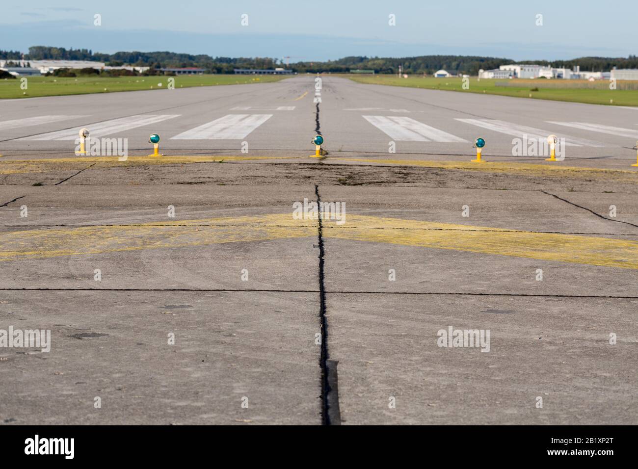 Straight view on empty runway / landing strip of a small airport near Munich. White markings on grey asphalt. Ready for take off and landing. Stock Photo