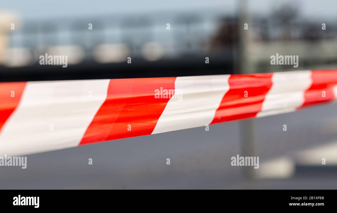 Close-up of red - white striped plastic tape. Used to shut off areas . E. g. construction sites, crime scenes, areas of danger. Blurry background. Stock Photo