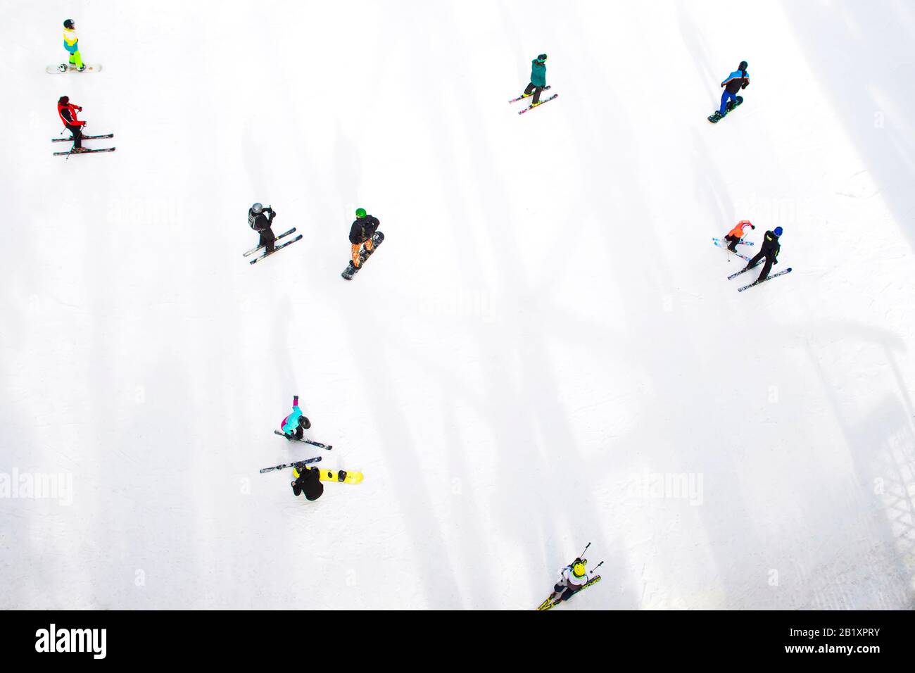 Top view of skiers and snowboarders riding on winter mountain. Stock Photo