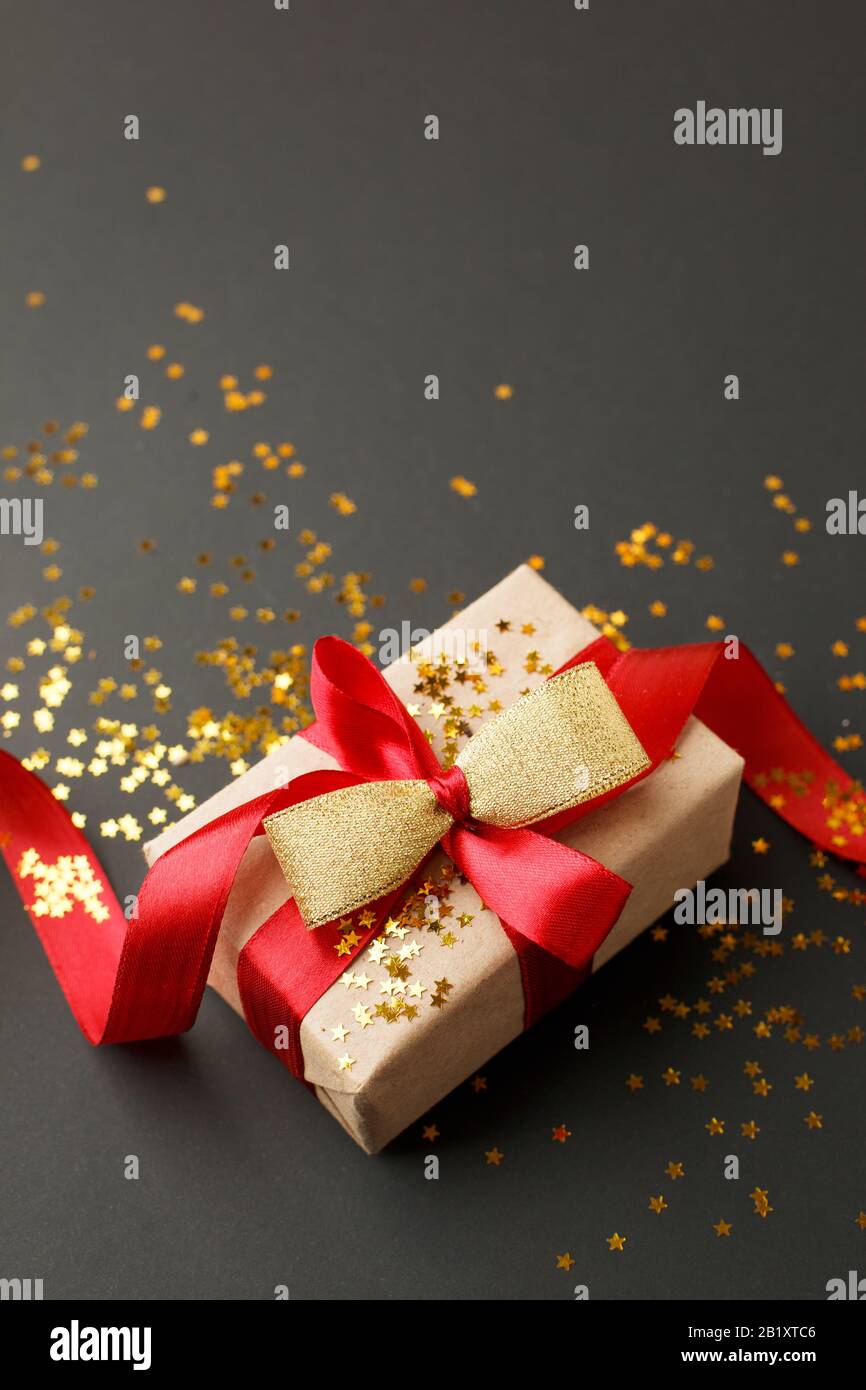 Gift or present box and gold stars confetti on black table top view. Flat lay composition for birthday, mother day, black friday sale, xmas, christmas Stock Photo