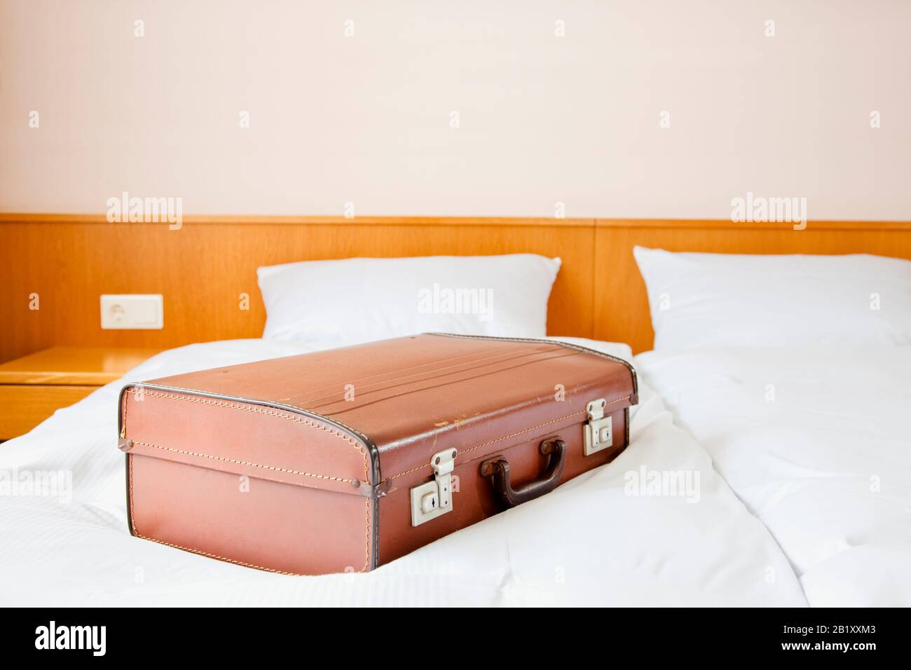 Old fashioned suitcase on a hotel room bed Stock Photo