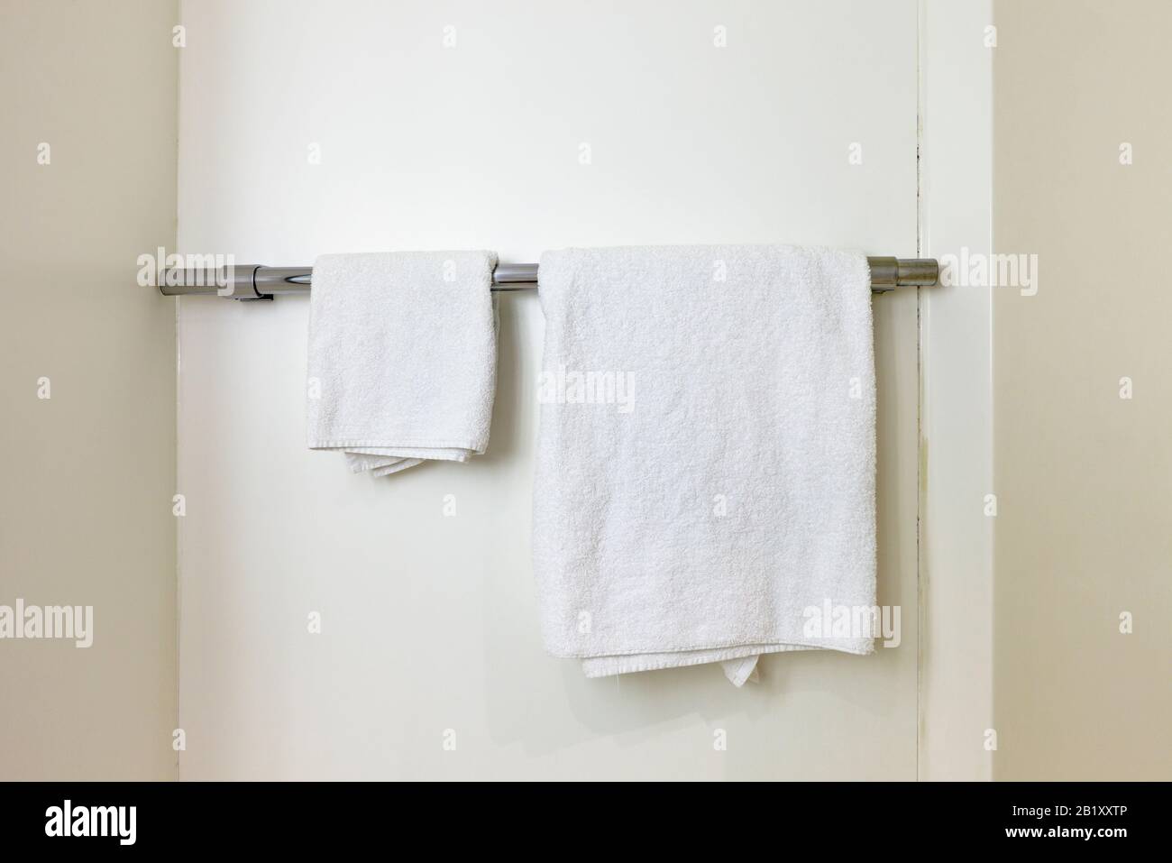 Basic white towels on a towel rail in a budget Motel bathroom, England, UK Stock Photo