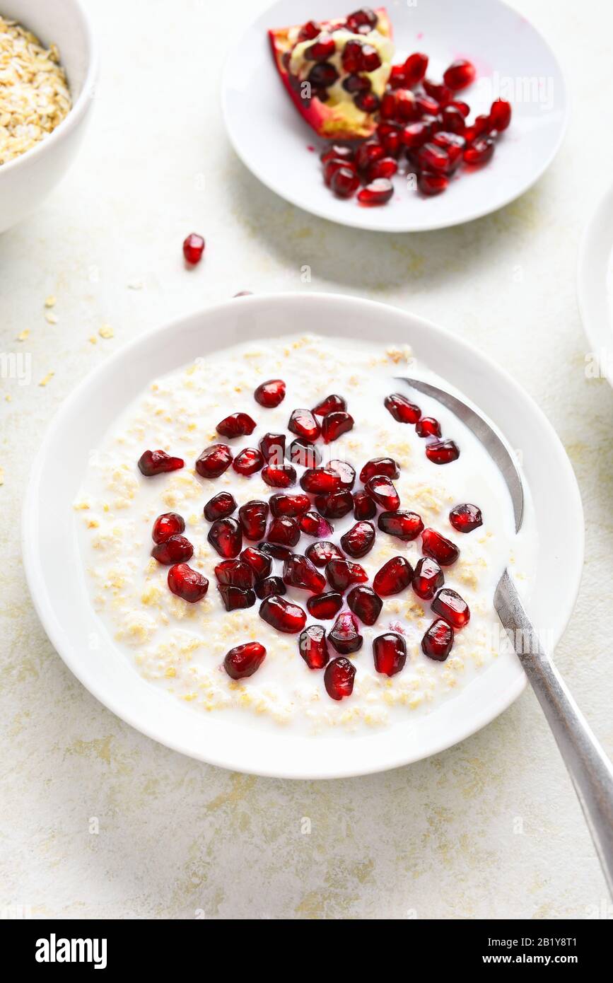 Pomegranate oats porridge in bowl over light stone background
