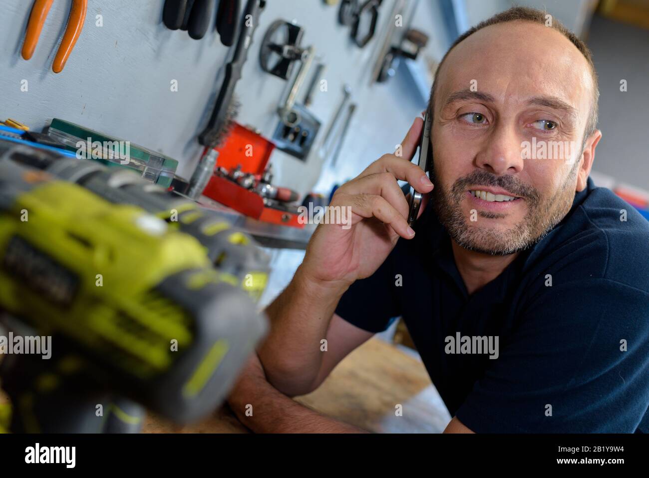 man using smartphone in workshop Stock Photo