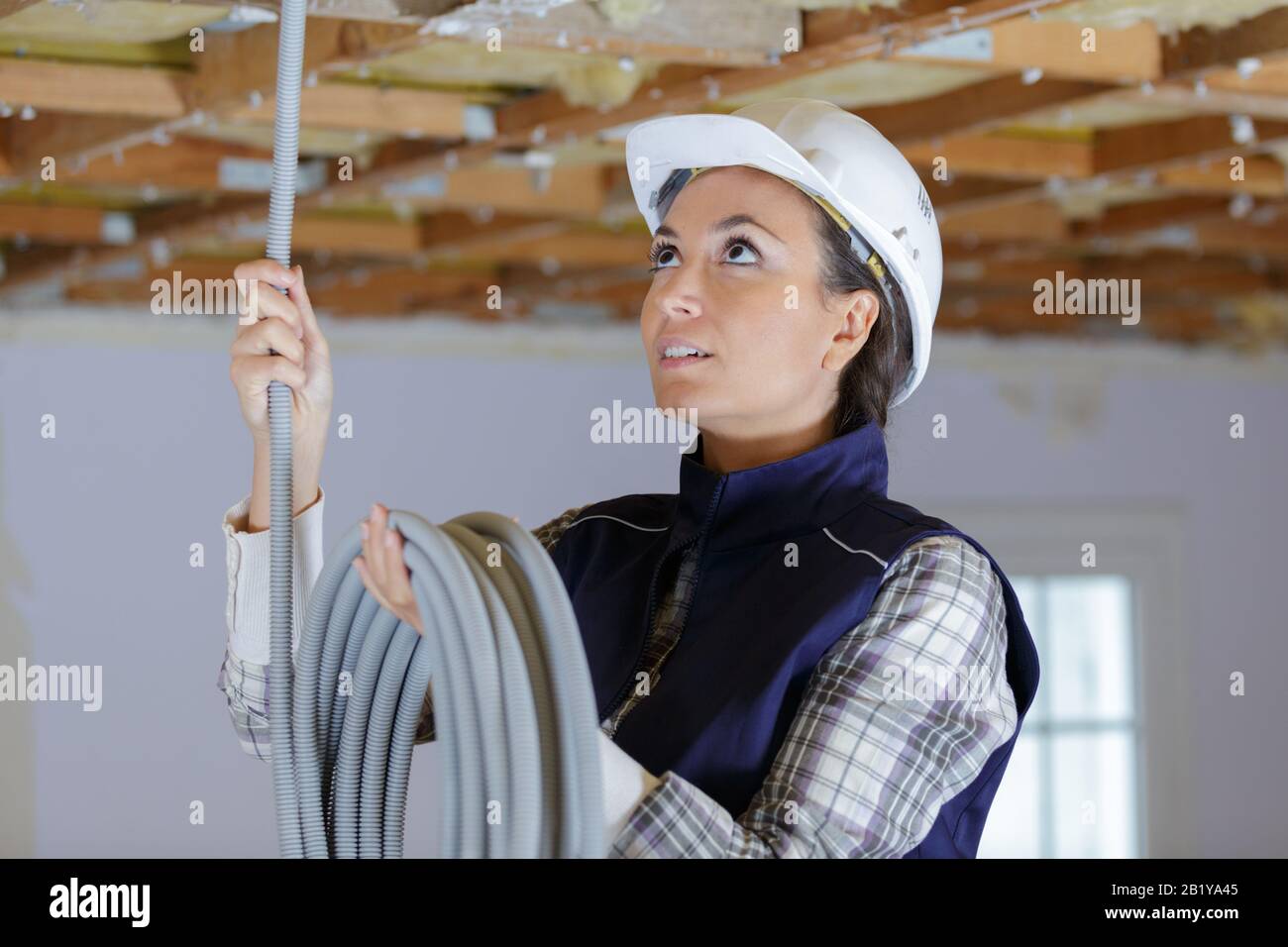 female electrician installing ventilation in ceiling Stock Photo