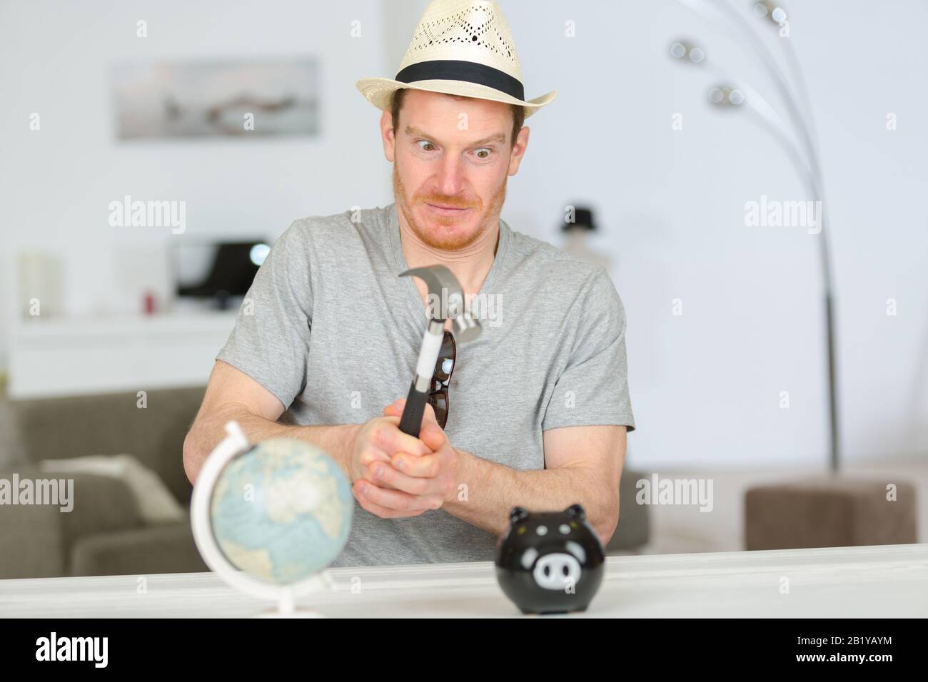 man about to break a piggy bank with a hammer Stock Photo - Alamy