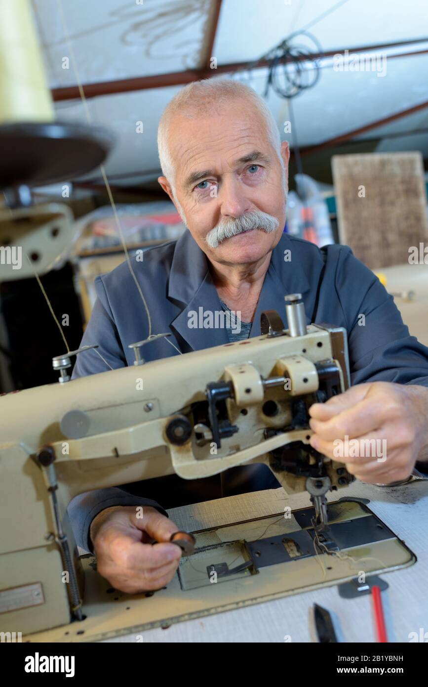 senior man using sewing machine Stock Photo