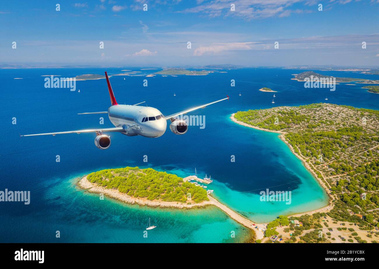 Airplane is flying over small islands and sea at sunny day Stock Photo