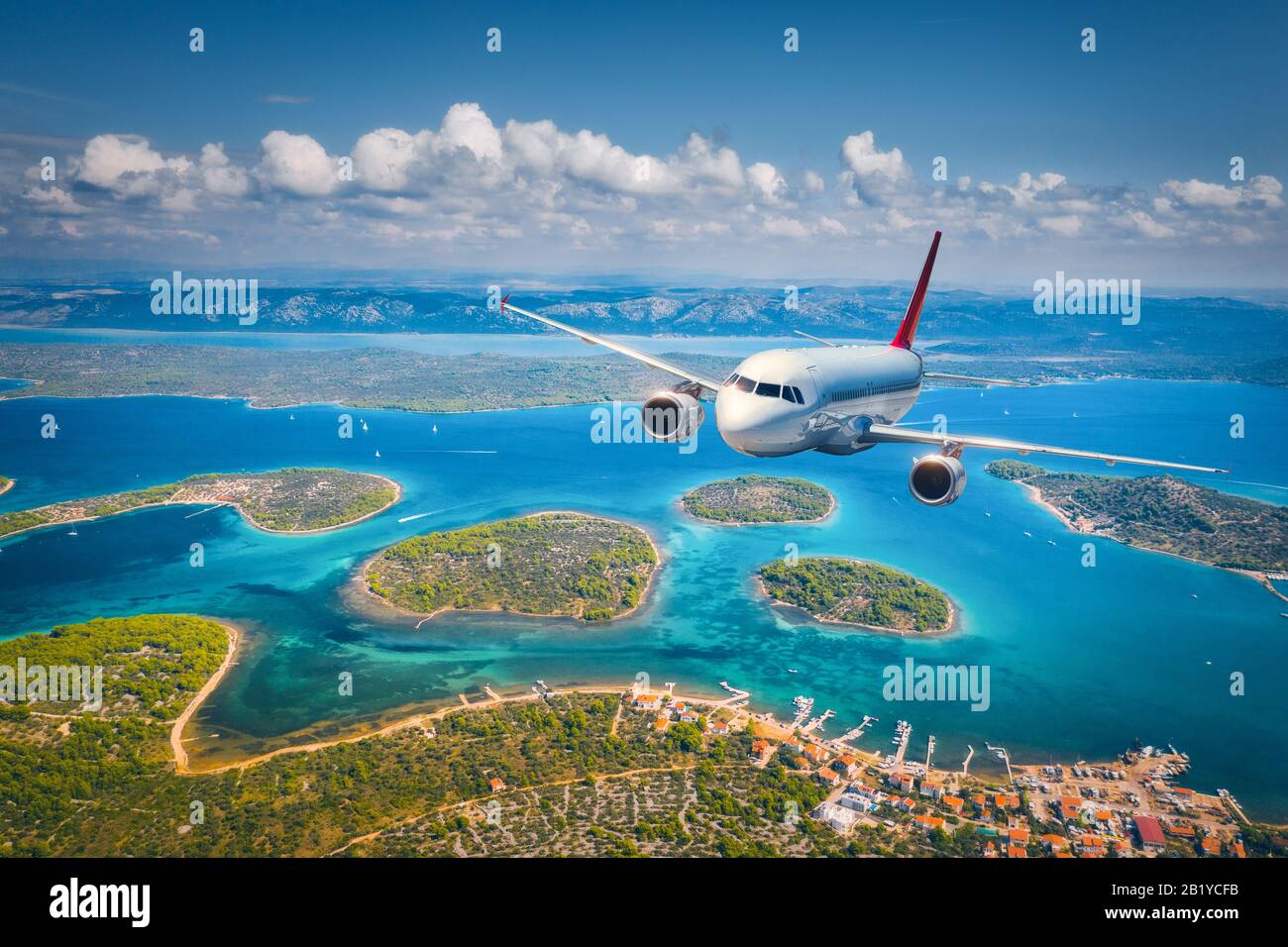 Airplane is flying over small islands and sea at sunny day Stock Photo