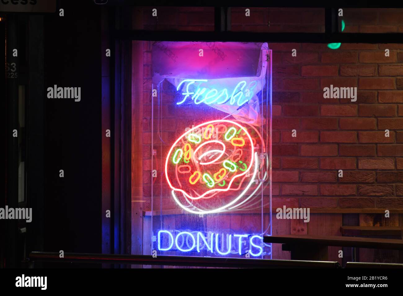 neon fresh donut sign in shop window at night Stock Photo