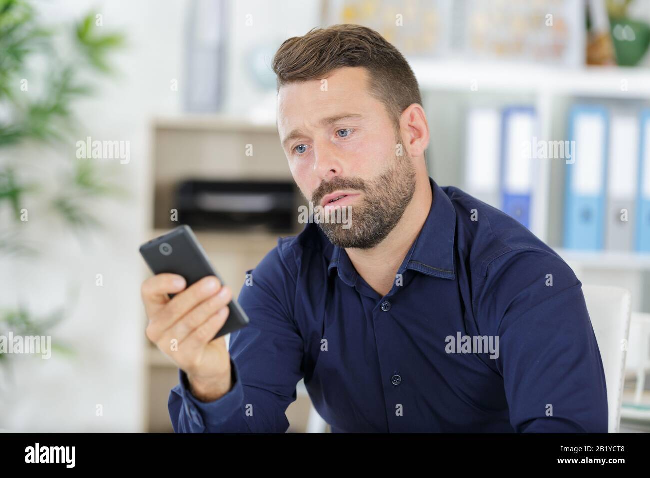 man using phone while sitting at desk in modern office Stock Photo