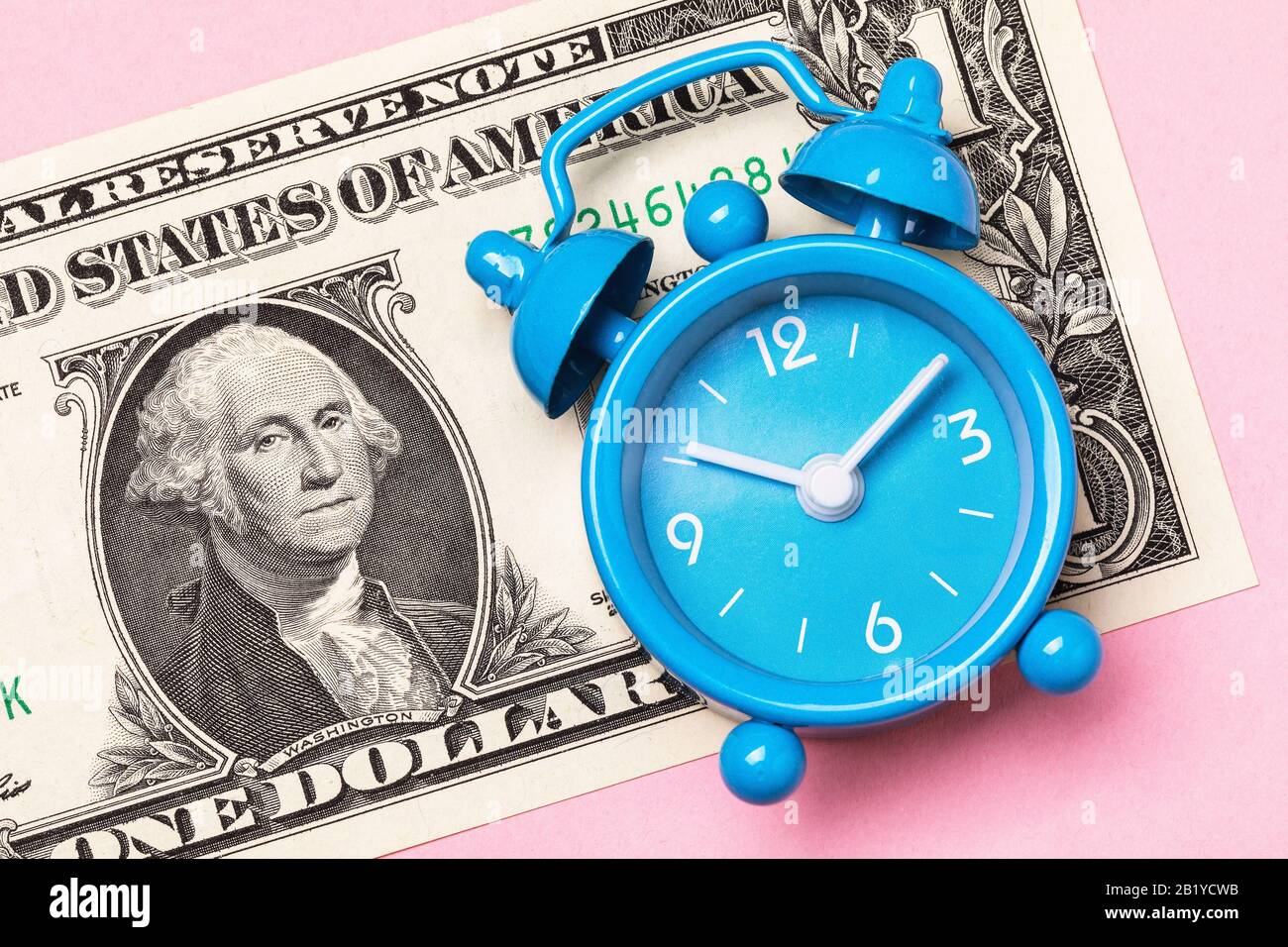 Alarm clock and 1 dollar on a pink background. Money time concept Stock