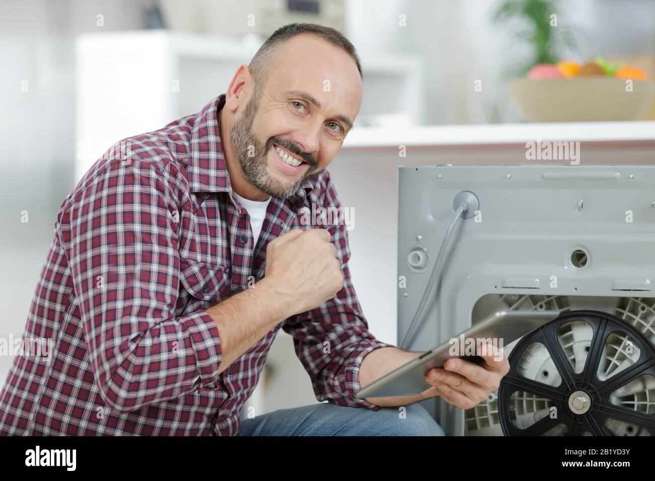 man using tablet pc to fix a washing machine Stock Photo