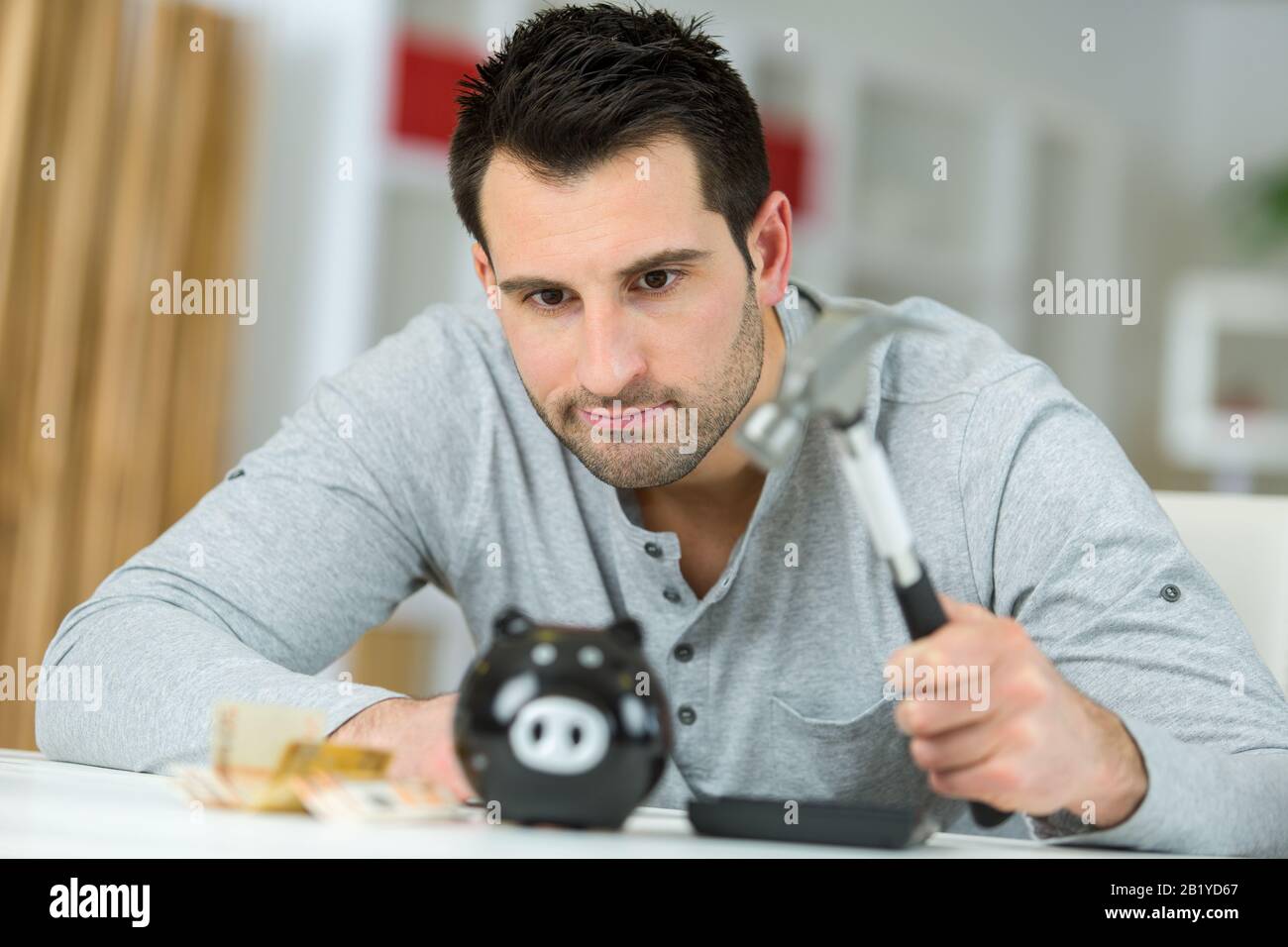 young man breaking piggy money bank with hammer Stock Photo - Alamy