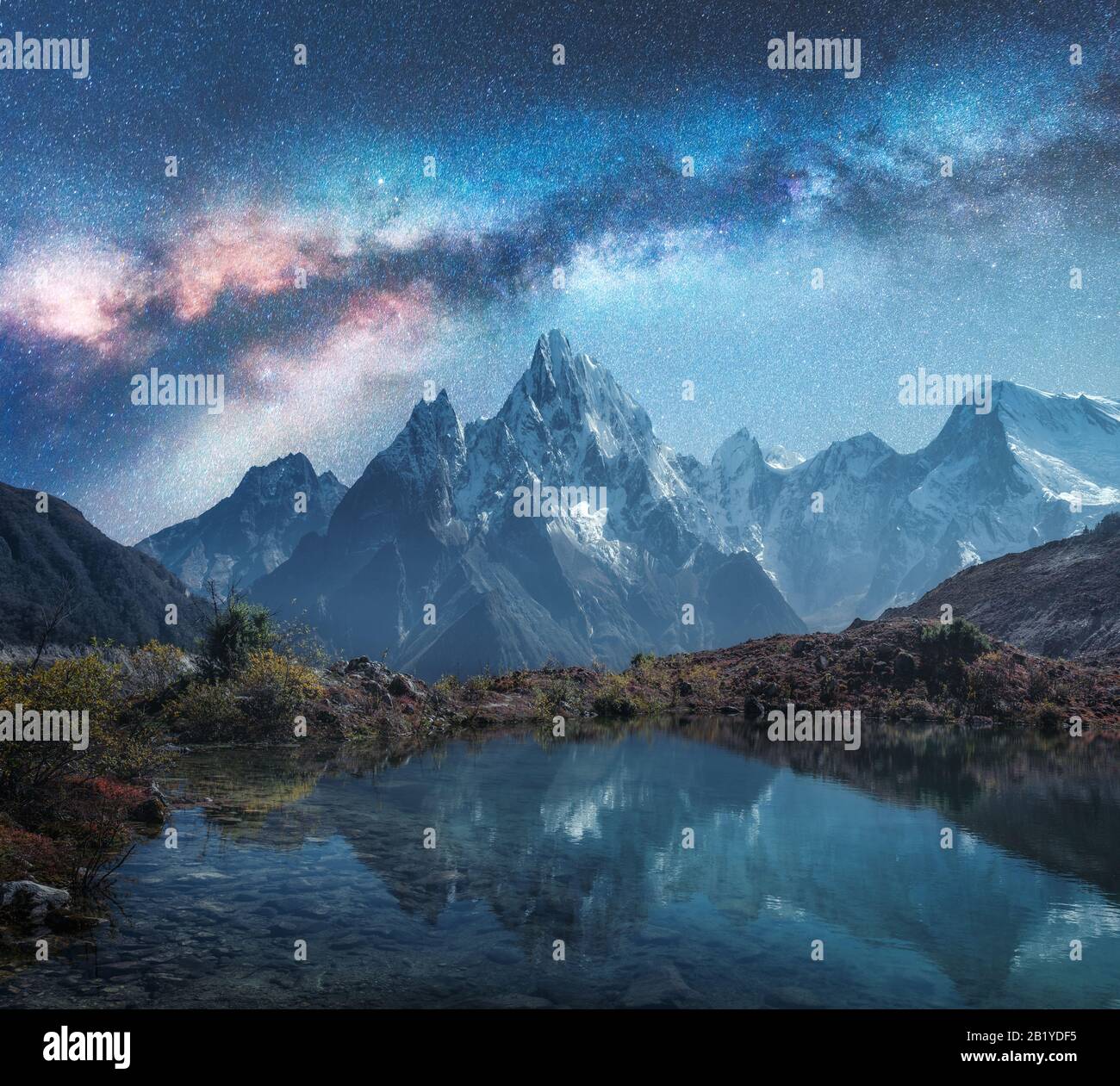 Milky Way over snowy mountains and lake at night. Landscape Stock Photo