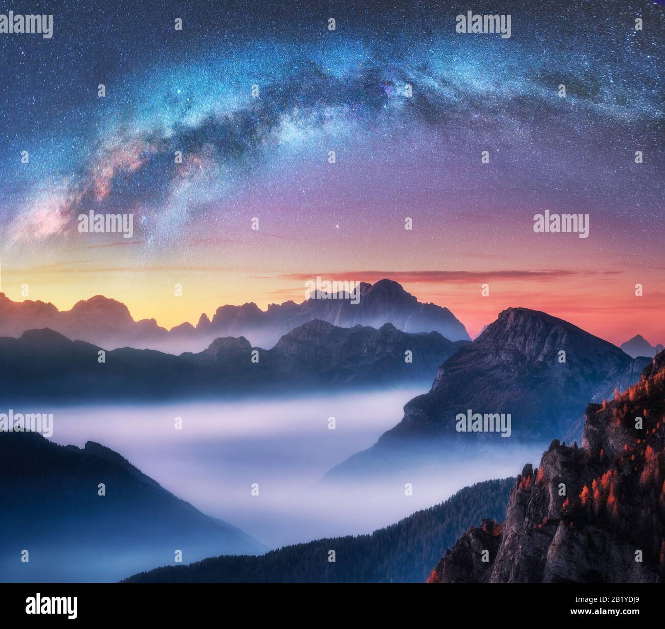 Milky Way above mountains in fog at night in summer Stock Photo