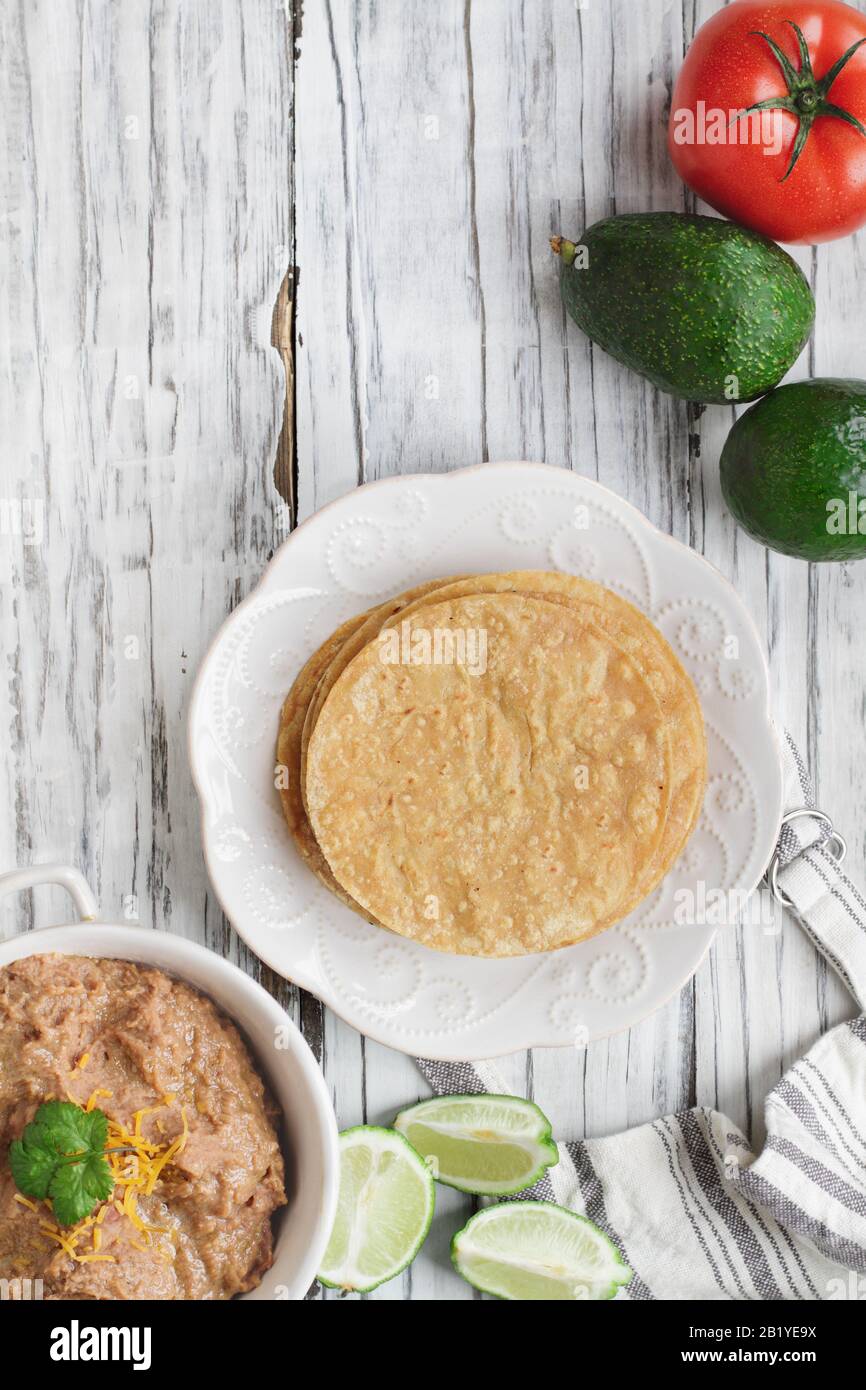 Corn tortillas with refried beans, avocados, tomatoes and fresh limes to make vegan tostadas