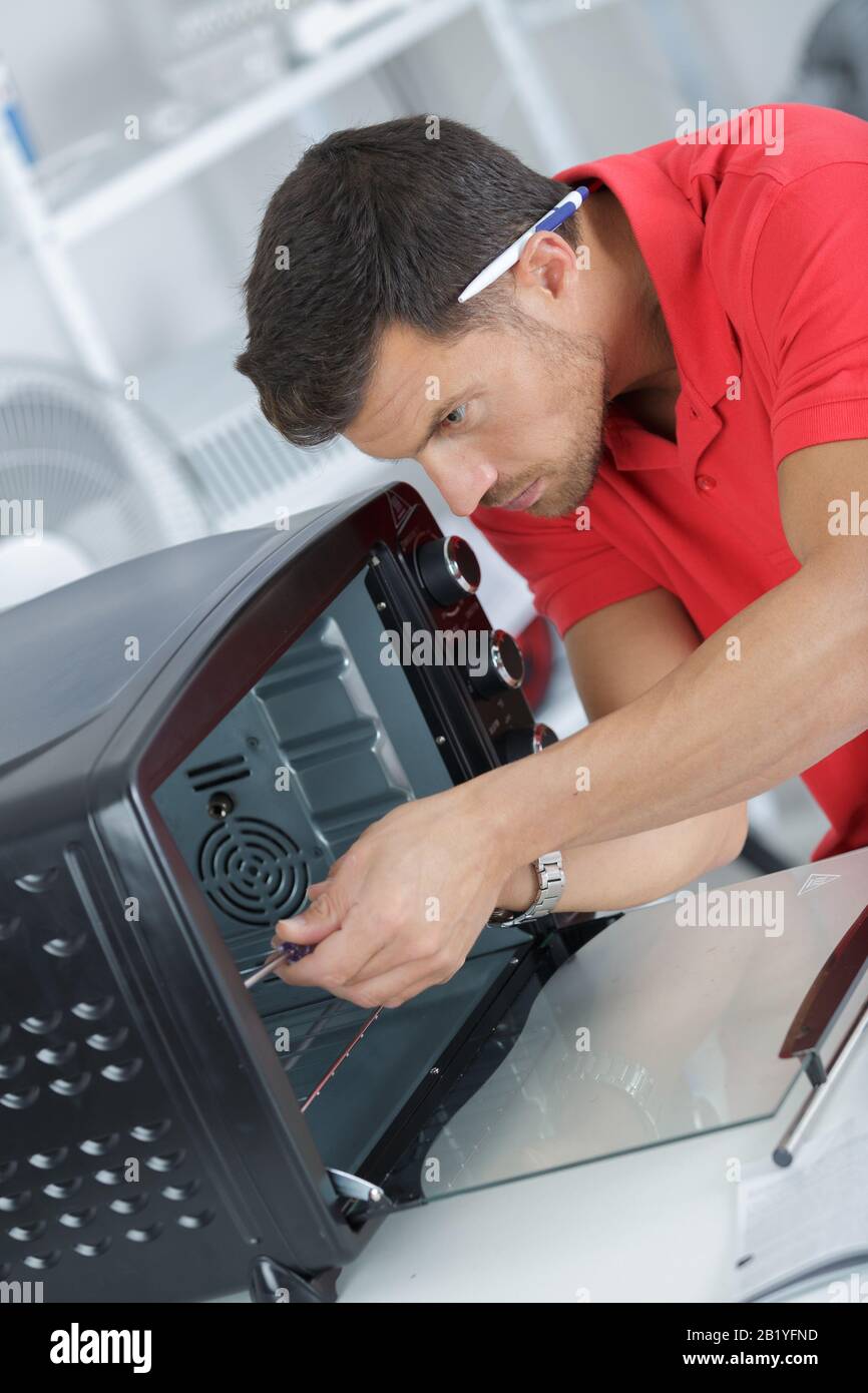technician in overall installing oven Stock Photo