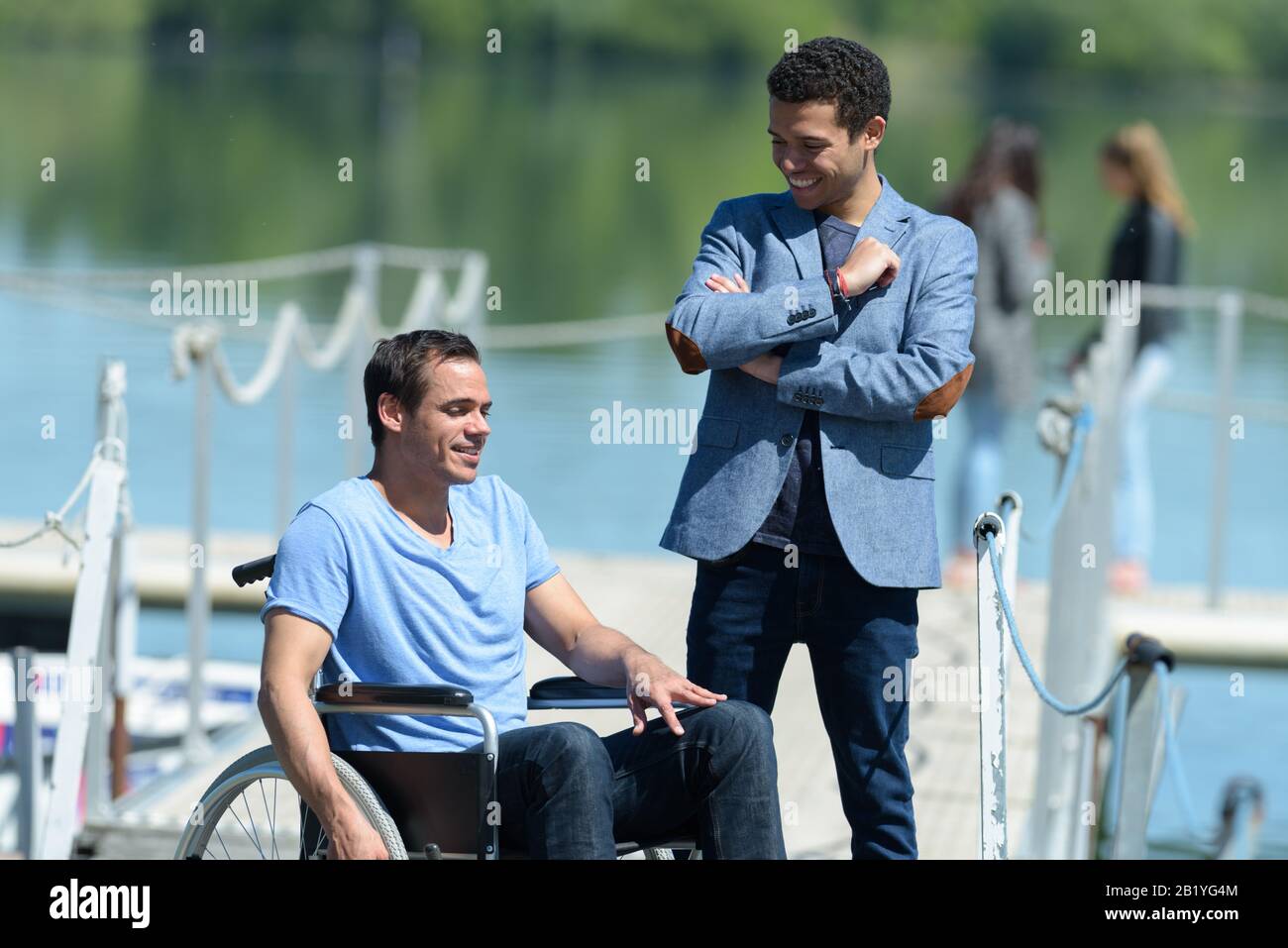 disabled young man in wheelchair with friend at lake Stock Photo - Alamy