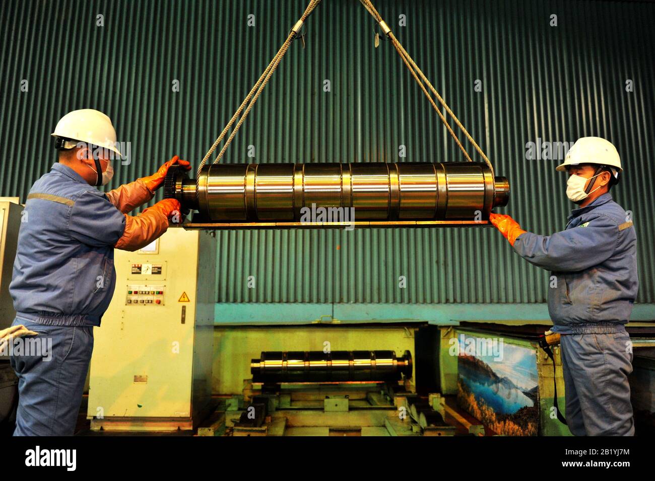 Chinese workers hoist stainless steel rollers at the plant of Qingdao