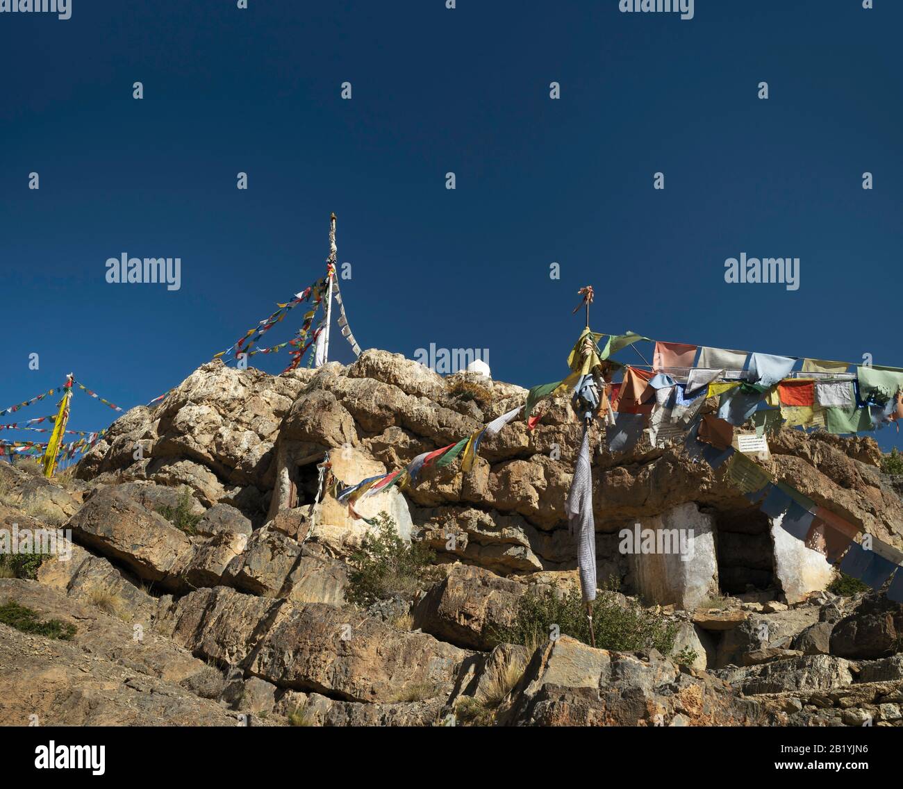 Rocky retreat for Buddhist monks with prayer flags high up in the Himalayas under blue sky near Kaza, Himachal Pradesh, India. Stock Photo