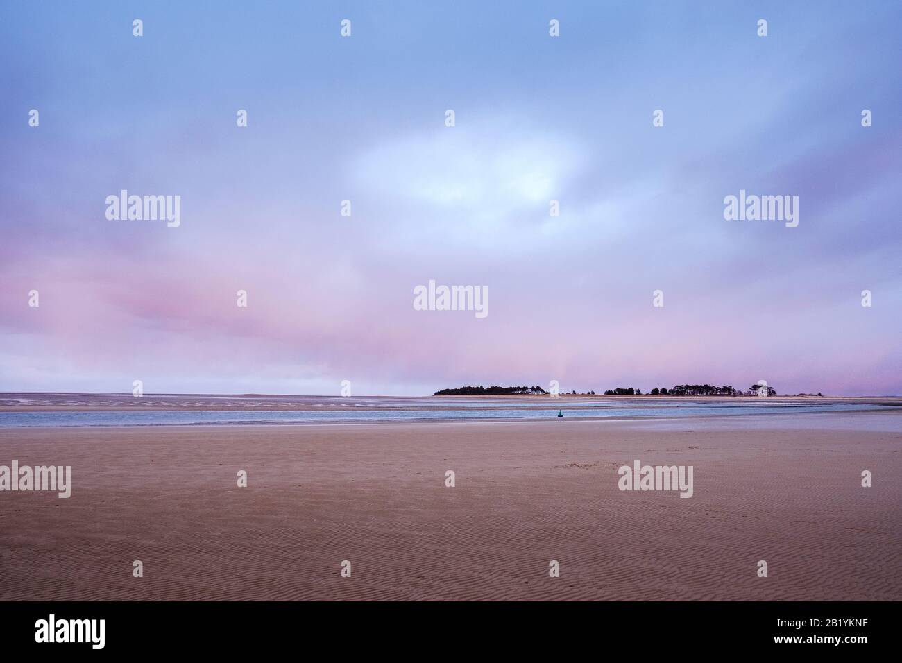 Pink clouds in a winter sunset over the sandy beach and main channel at Wells-next-the-Sea. Stock Photo