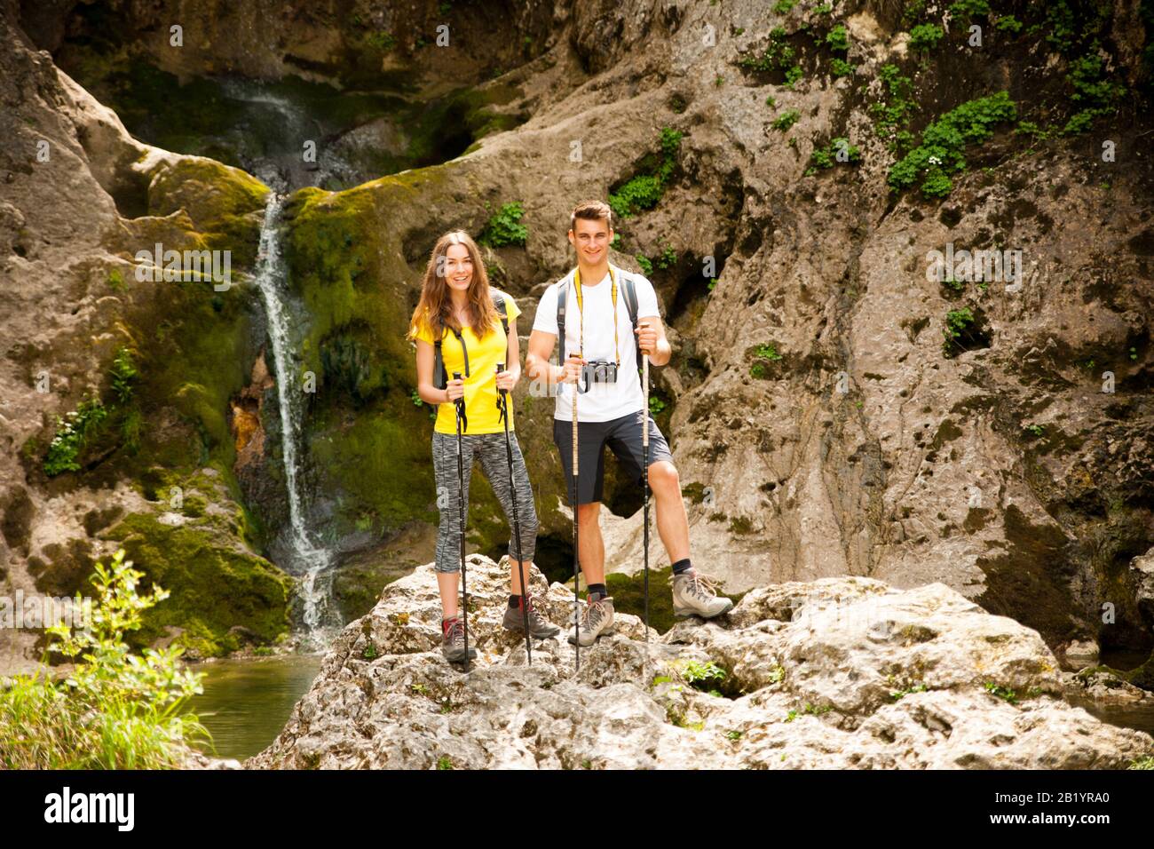 active young couole hiking in nature resting near waterfalll and taking pictures with camera Stock Photo