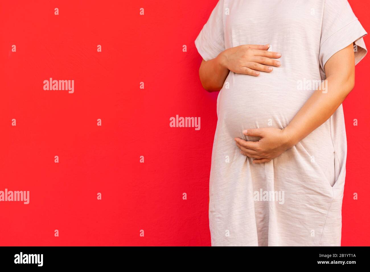 Pregnant woman feeling happy at home while taking care of her child. The young expecting mother holding baby in pregnant belly. Maternity prenatal car Stock Photo